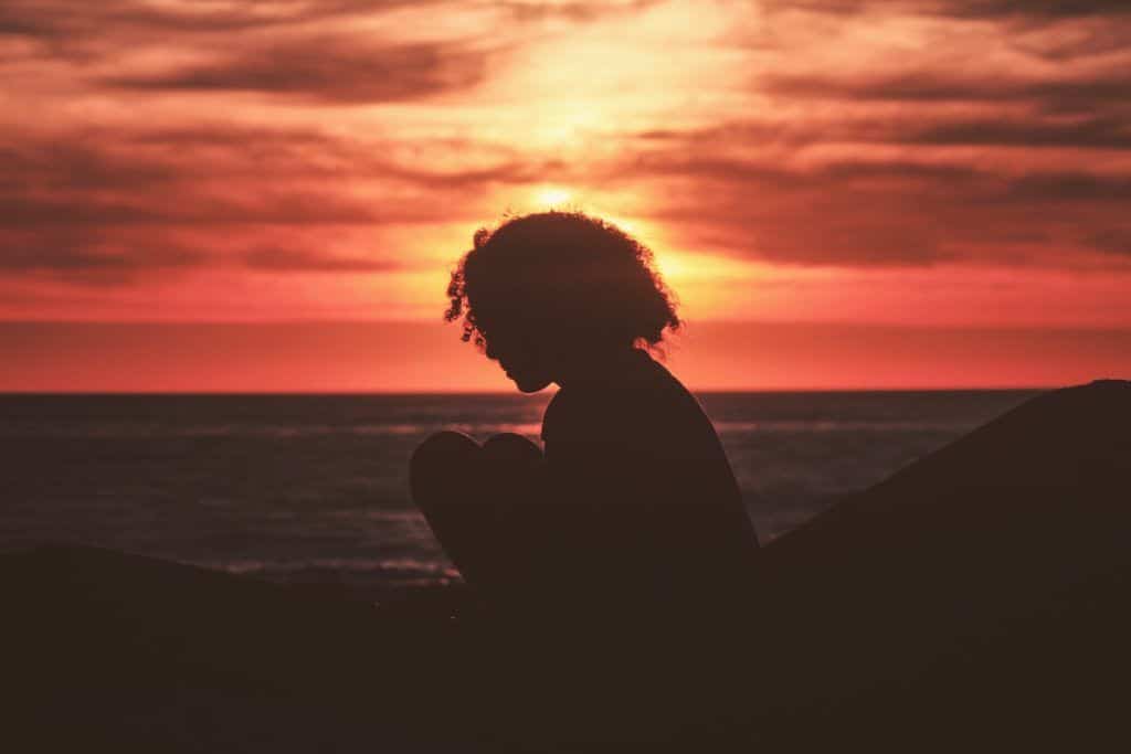 Personne assise sur la plage au coucher du soleil