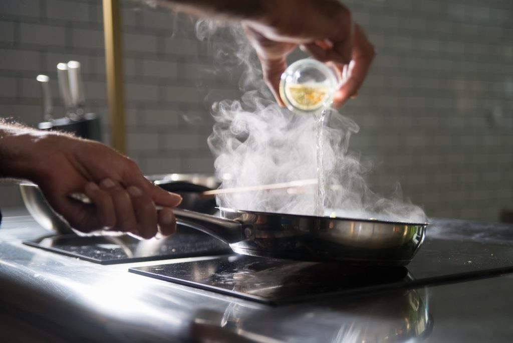 Une personne cuisine sur une cuisinière électrique à l’aide d’une poêle à frire