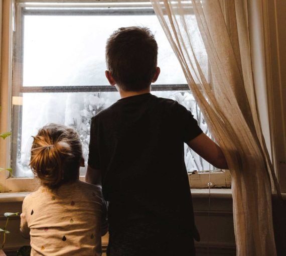 Enfants regardant par la fenêtre en hiver