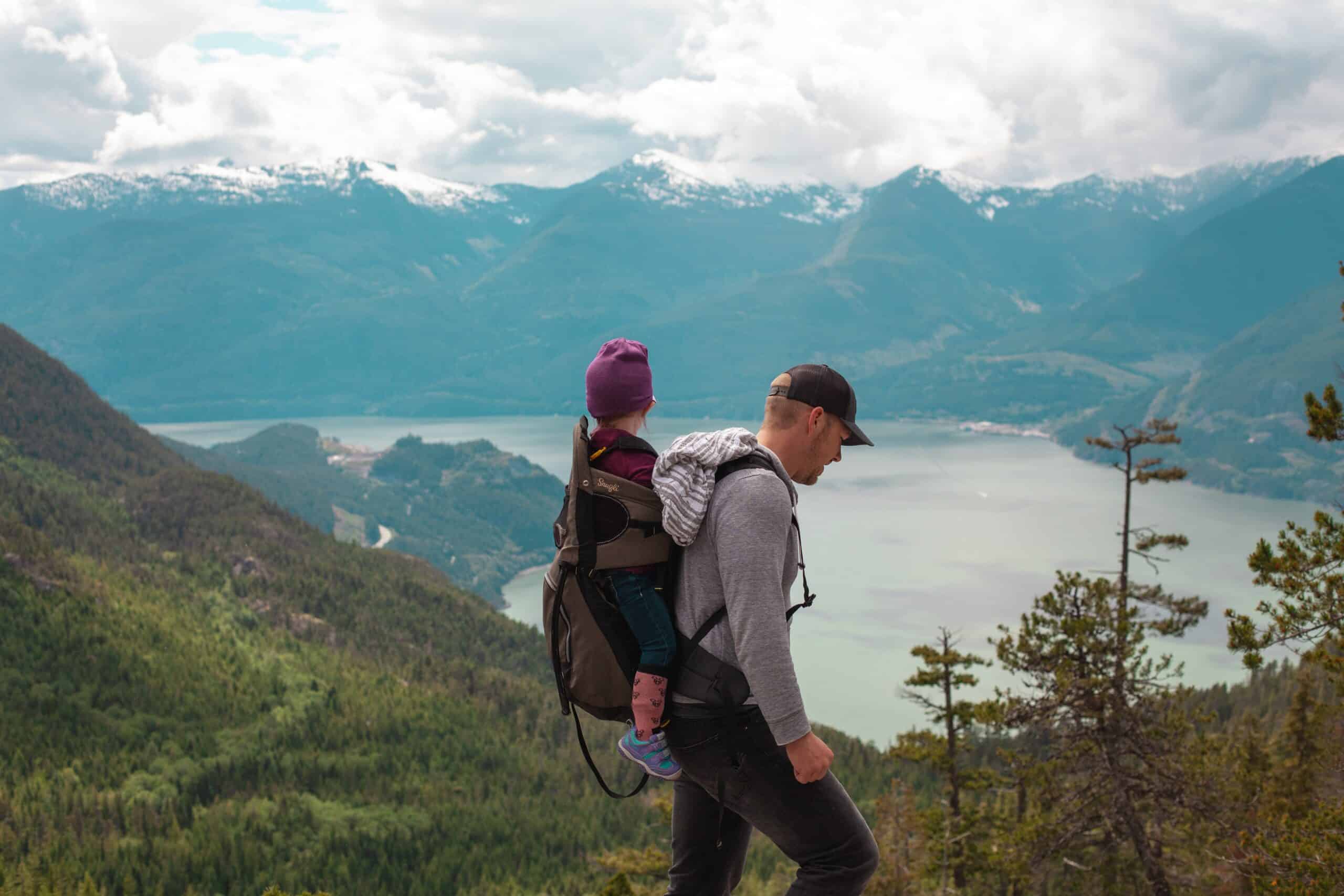 Un homme marche au sommet de la montagne avec un enfant sur le dos.