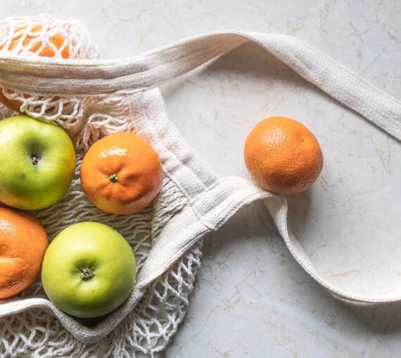 Oranges et pommes vertes dans un sac tricoté réutilisable
