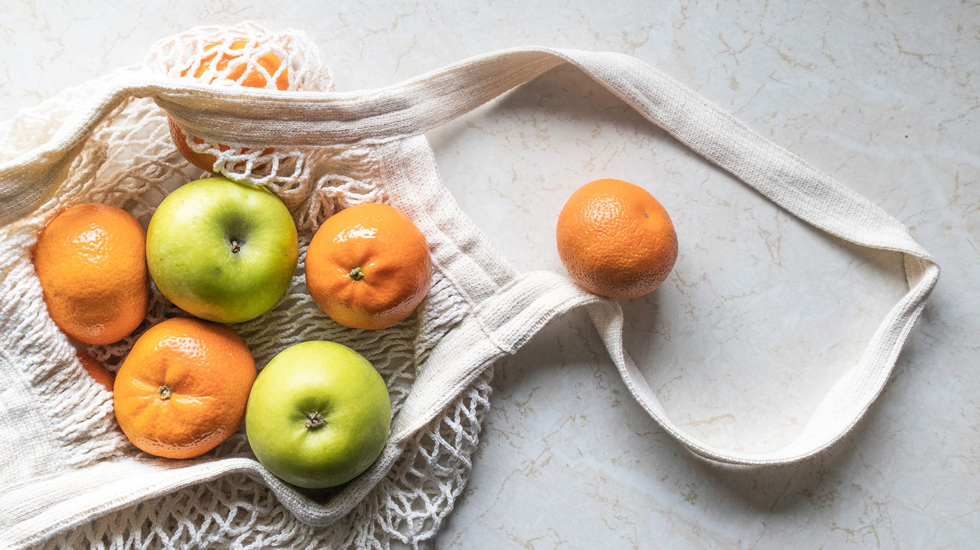 Oranges et pommes vertes dans un sac tricoté réutilisable