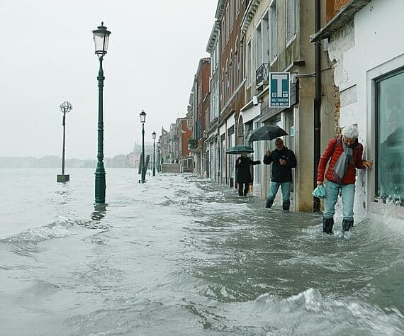 Les gens se débattent le long d’un étroit sentier à Venise, jusqu’à mi-mollet dans l’eau en mouvement, le matin après les inondations catastrophiques de 2019.