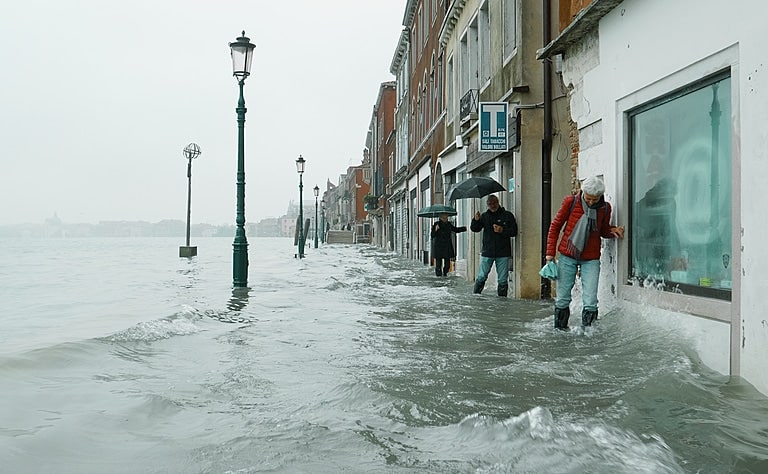 Les gens se débattent le long d’un étroit sentier à Venise, jusqu’à mi-mollet dans l’eau en mouvement, le matin après les inondations catastrophiques de 2019.