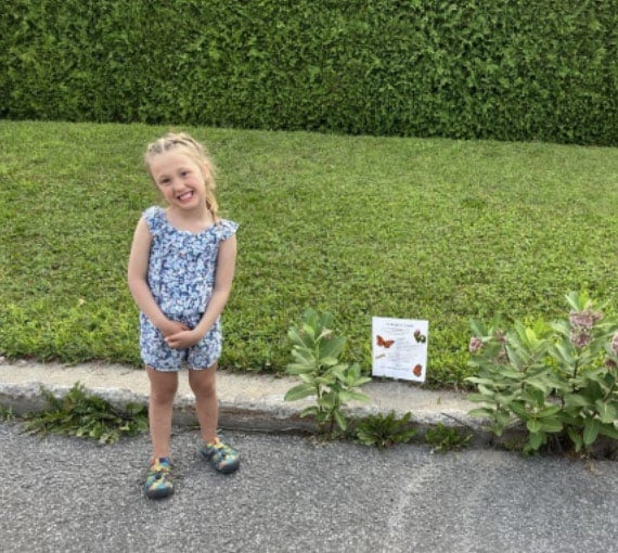 Flora, 5 ans, après avoir posé sa pancarte de sensibilisation, qui indique l’importance de ne pas couper les plants d’asclépiades.